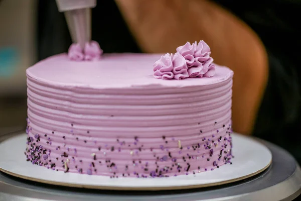 cake chef designer using pink cream filling on layered frosted chocolate lilac cake at kitchen lab