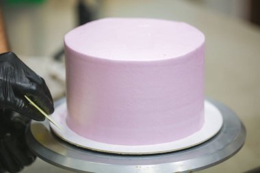 Pasta şefi spatula ve kazıyıcı kullanarak pürüzsüz katmanlı leylak kremalı pasta - düğün pastası hazırlığı