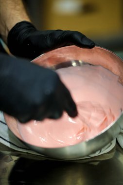 Pasta şefi doğum günü pastası için beyaz çikolata pembesi dolgusu hazırlıyor. kek dekorasyonu