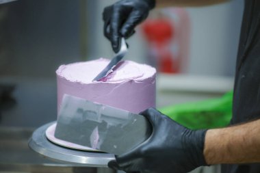 Pasta şefi spatula ve kazıyıcı kullanarak pürüzsüz katmanlı leylak kremalı pasta - düğün pastası hazırlığı