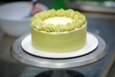 Pasta şefi kremalı helezon fıstıklı girdaplar yapıyor katmanlı yeşil çikolatalı pasta