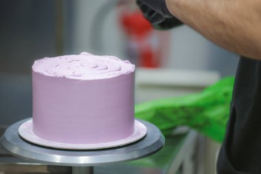 Pasta şefi spatula ve kazıyıcı kullanarak pürüzsüz katmanlı leylak kremalı pasta - düğün pastası hazırlığı