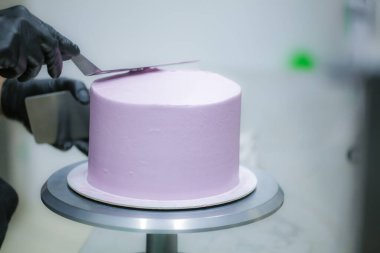 Pasta şefi spatula ve kazıyıcı kullanarak pürüzsüz katmanlı leylak kremalı pasta - düğün pastası hazırlığı