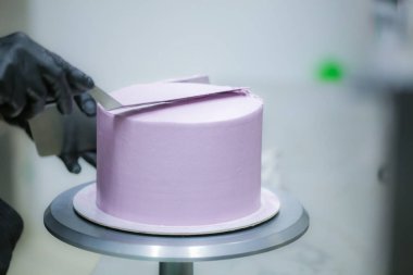 Pasta şefi spatula ve kazıyıcı kullanarak pürüzsüz katmanlı leylak kremalı pasta - düğün pastası hazırlığı