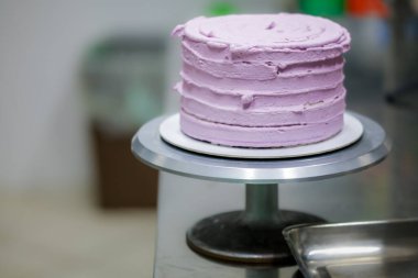 Pasta tasarımcısı, mutfak laboratuarında gül kremi dolgu poşeti, katmanlı siyah çikolatalı pasta kullanıyor.