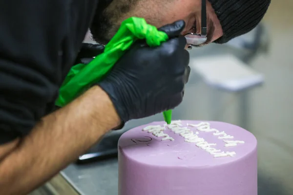 cake designer topping lilac purple frosted cake hand writing emotional regret message with white whipped cream filling