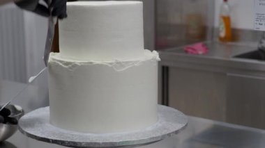 cake designer spinning smoothing and levelling frosted two floorwhite wedding cake with spatula and scraper 4k footage