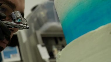 chef pastry desginer sing edible blue airbrush colour to decorate two floor layered frosted cake in blue white 4k footage