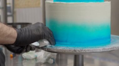 cake designer spinning smoothing and levelling frosted grandient blue white wedding cake with spatula and scraper 4k footage