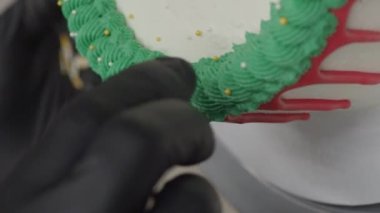 pastry chef cake designer decorating christmas red green white frosted cheesecake with piping bag 4k footage