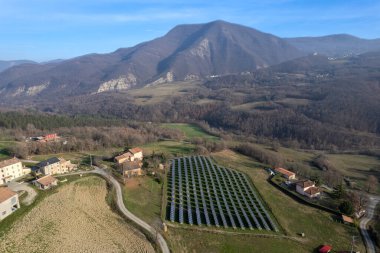 Solar cell photovoltaic panel in country landscape against sunny sky and mountain background.