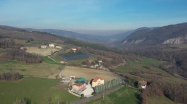 Solar cell photovoltaic panel in country landscape against sunny sky and mountain background drone footage.