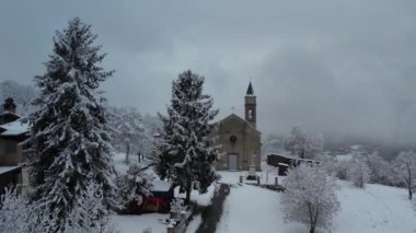 Aerial footage of winter landscape near italian apennines town parish covered in snow in a little town called Castelletto, Verncasca Italy