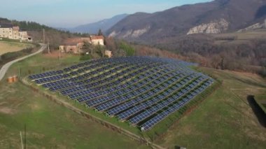 Solar cell photovoltaic panel in country landscape against sunny sky and mountain background drone footage.