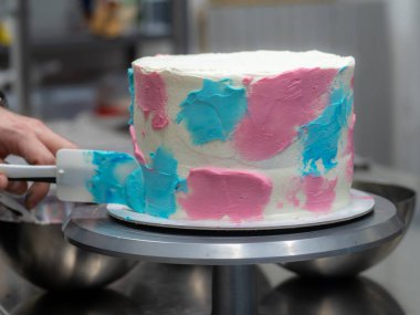 chef pastry designer confectioning a frosted 3 floor layered cake decorated with pastel creamy colors photo.