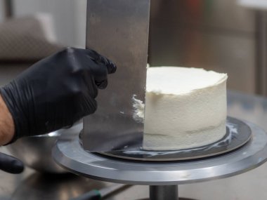 chef pastry designer confectioning a frosted 3 floor layered cake stuffed with strawberries , blueberries and whipped butter cream. Cake structure before decoration.