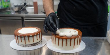 chef pastry baker preparing salty caramel frosted dripping white cakes with meringues on top
