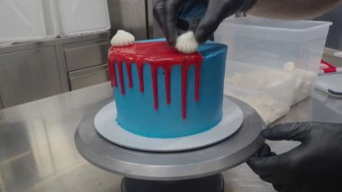 Mavi spreyli pasta tezgahın üzerine damlatılmış kırmızı ganache dolgu ve beyaz kremalar ve en üstteki 4K görüntülerde krema.