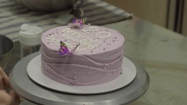 20 yıllık krema kaplı pasta üzerine harf harfleri, kelebekler, inciler, fırıncı tasarımcı tarafından serpiştirilmiş.