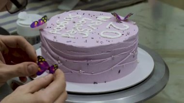 20 yıllık krema kaplı pasta üzerine harf harfleri, kelebekler, inciler, fırıncı tasarımcı tarafından serpiştirilmiş.