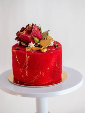 Buzlu kırmızı kadife pasta, çiçek ve kalp kaplamalı ve beyaz arka plan üzerine altın boya vuruşları.
