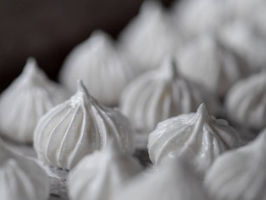 pastry chef baker artisan making white swirl and twirl meringue cones with piping bag filled with egg cream and sugar to bake for sweet preparation