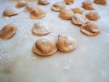 Closeup process making tortelli stuffed with pumpkin filling homemade pasta, grandma cook seasonal 'tortelli di zucca', traditional italian filled pasta, senior woman cooking food on kitchen