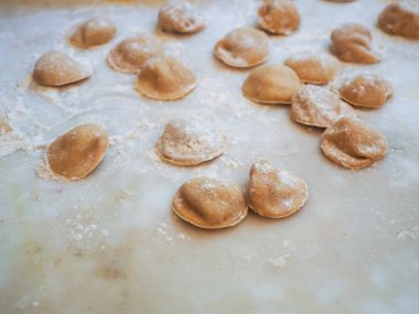 Closeup process making tortelli stuffed with pumpkin filling homemade pasta, grandma cook seasonal 'tortelli di zucca', traditional italian filled pasta, senior woman cooking food on kitchen