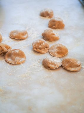 Closeup process making tortelli stuffed with pumpkin filling homemade pasta, grandma cook seasonal 'tortelli di zucca', traditional italian filled pasta, senior woman cooking food on kitchen