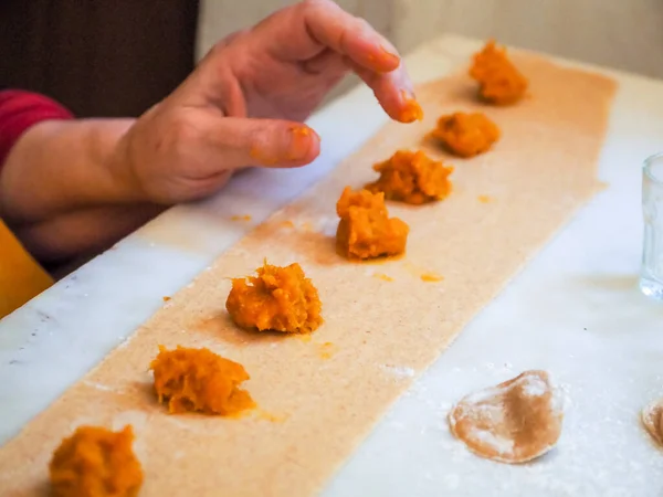 senior woman preparing stuffed pumpkin ravioli tortelli with wholewheat italian grain flour at home, homemade food concept