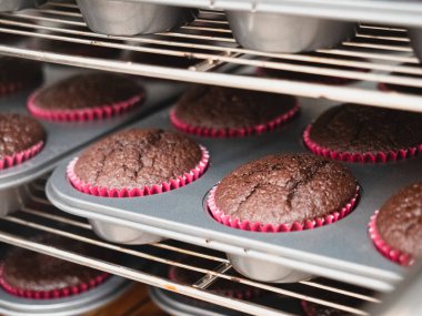 Pasta şefi büyük bir grup koyu kırmızı kadife çikolatalı kek pişiriyor profesyonel havalandırmalı fırında kekler, catering şirketinde küçük zanaatkar üretimi