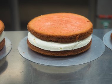 Tanımlanamayan pasta şefi üç katlı bir pasta hazırlıyor, süngerimsi kırmızı kadife katmanları tereyağı ve karamel ile birleştiriyor.