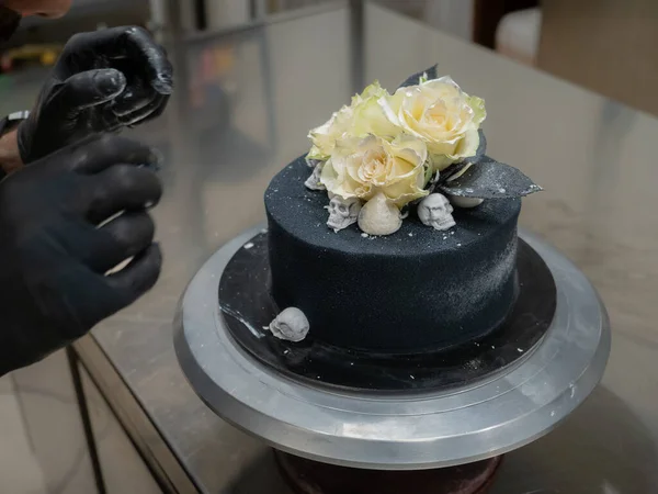 糕点主厨烘培生日涂满糖霜的黑毛刷蛋糕 两朵真正的玫瑰镀银和可食用的巧克力头骨顶盖 银刷笔划 — 图库照片