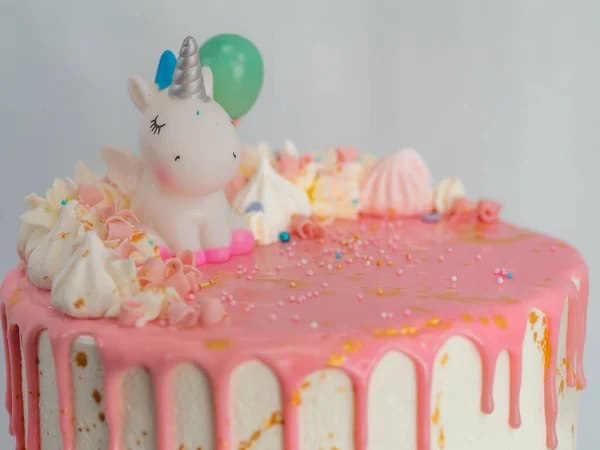 粉色结霜滴糖霜白生日蛋糕 配上独角兽 配料和洒水的配料 倒立在金黄色的可食用油漆笔刷上 — 图库照片