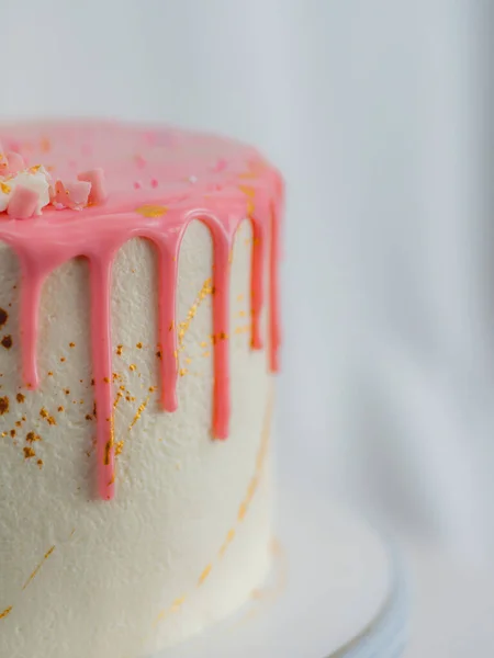 粉色结霜滴糖霜白生日蛋糕 配上独角兽 配料和洒水的配料 倒立在金黄色的可食用油漆笔刷上 — 图库照片