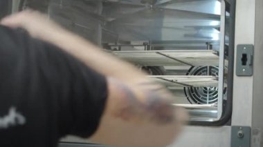 Pasta şefi, profesyonel fırında bir kaç tepside büyük bir grup çikolatalı kek pişiriyor. 4K görüntü.