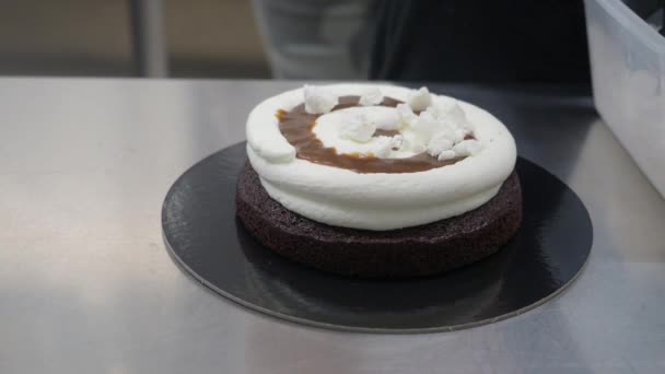 ペストリーシェフはバタークリーム キャラメル メレンゲの塊でスポンジのようなダークチョコレート層を組み立て 層状の焼き菓子を準備します — ストック動画