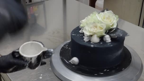 ペストリーシェフパン屋トッピング誕生日黒エアブラシ塗装霜ケーキ 2つの本物のバラ銀スプレーと食用チョコレート頭蓋骨のトッパー 銀ブラシストローク — ストック動画