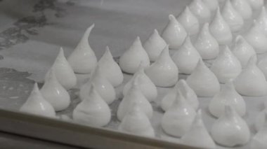 Pasta şefi fırıncı beyaz girdap yapıyor ve krema ve şeker dolu boru torbasıyla kremalı krema ve krema çeviriyor.