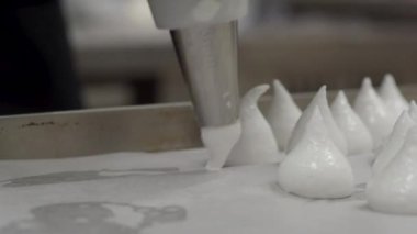 Pasta şefi fırıncı beyaz girdap yapıyor ve krema ve şeker dolu boru torbasıyla kremalı krema ve krema çeviriyor.