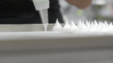 Pasta şefi fırıncı beyaz girdap yapıyor ve krema ve şeker dolu boru torbasıyla kremalı krema ve krema çeviriyor.