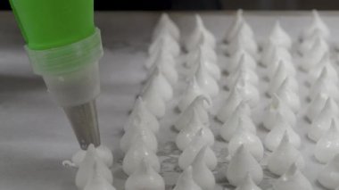 Pasta şefi fırıncı beyaz girdap yapıyor ve krema ve şeker dolu boru torbasıyla kremalı krema ve krema çeviriyor.