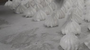 pastry chef baker artisan making white swirl and twirl meringue cones with piping bag filled with egg cream and sugar to bake for sweet preparation