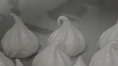 pastry chef baker artisan making white swirl and twirl meringue cones with piping bag filled with egg cream and sugar to bake for sweet preparation