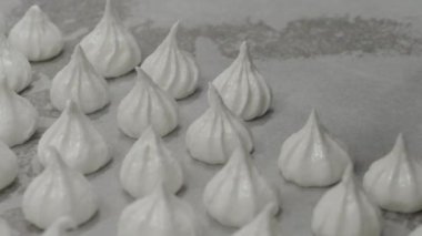 pastry chef baker artisan making white swirl and twirl meringue cones with piping bag filled with egg cream and sugar to bake for sweet preparation