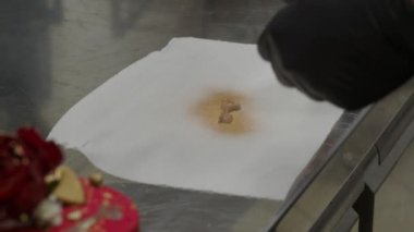Şef anahtar şeklindeki çikolatalı pasta üstüne altın boya sıktı. 4K görüntü.