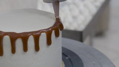 Hamur işi aşçısı güve beyazı kremalı keki bitiriyor. Karamel şurubu damlıyor ve el yapımı kremalar. 4K görüntüler.