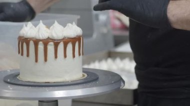 Hamur işi aşçısı güve beyazı kremalı keki bitiriyor. Karamel şurubu damlıyor ve el yapımı kremalar. 4K görüntüler.