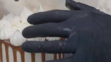 Hamur işi aşçısı güve beyazı kremalı keki bitiriyor. Karamel şurubu damlıyor ve el yapımı kremalar. 4K görüntüler.