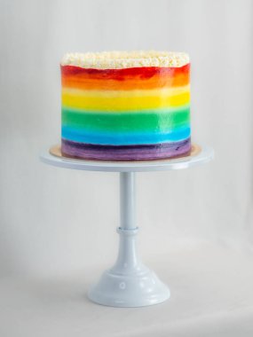 Pasta şefi düğün partisi için lgbt gökkuşağı renginde buzlu kek üzerinde çalışıyor. Doğum günü pastası. Gökkuşağı kağıt bardak kağıtları. Doğum günün kutlu olsun. Tatilleri kutluyoruz. LGBT gururu.